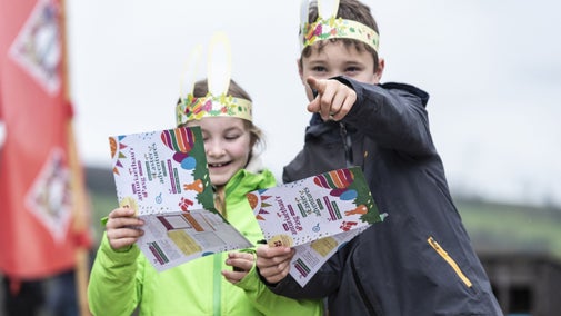 Two children wearing paper bunny ears and holding printed trail sheets on an Easter egg hunt